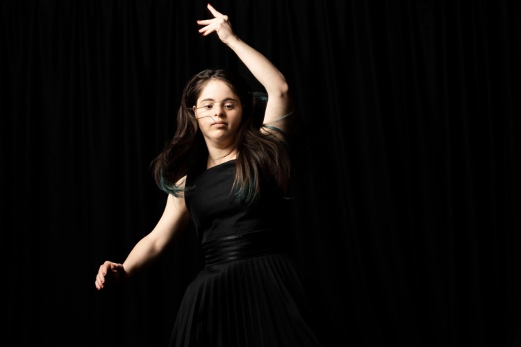 Jianna dancing in a black dress against a black background