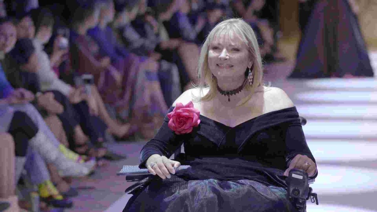 Carol Taylor on the runway dressed in an off the shoulder black gown