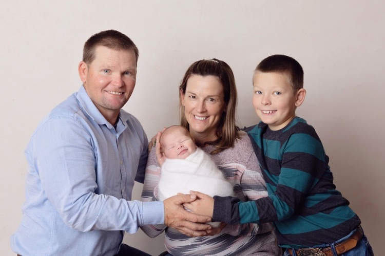 Smiling woman with baby in arms, with a smiling man on one side and a smiling boy o her other side