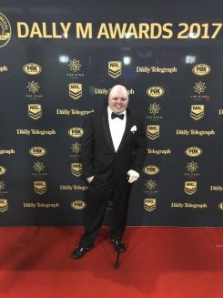 Dean Clifford in a black and white suit on the red carpet at a formal awards event.