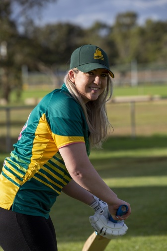 A woman is standing outside holding a cricket bat.