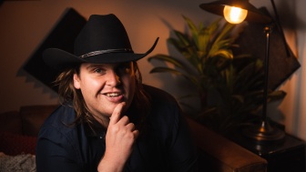 A young man with a cowboy hat smiles