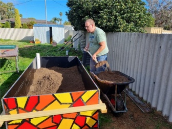 Brendan working in the garden with a shovel and wheel barrow...