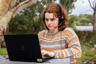 Amber sitting at a park bench with her laptop