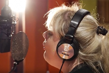 NDIS participant Belinda with headphones on singing into a microphone.