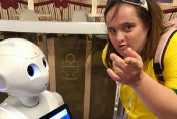 Shona interacts with a robot, she points toward the camera