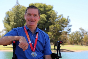 Chris sits in his wheelchair wearing his Sailability Championship medal 