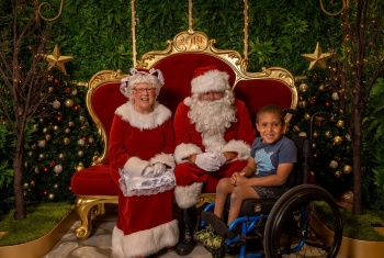 Caelin sits in his chair next to Santa and Mrs Claus