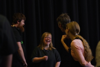 Back to Back Theatre performers laugh while they rehearse in a group
