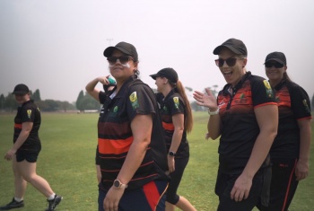 The women at the National Cricket Inclusion Championships wave at the camera as they walk onto the ground in their uniforms