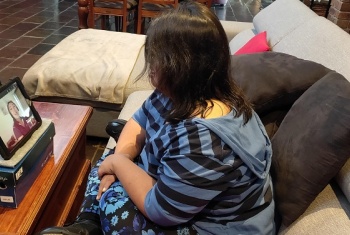 Casey sits on her couch and has a video session on her iPad