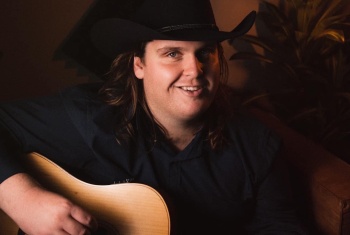 A young man with a cowboy hat plays a guitar