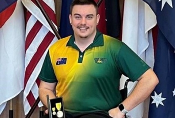 Braedon in his wheelchair holding a medal wearing an Australian sports top.