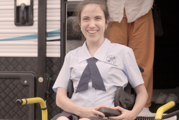 Hannah in her wheelchair smiling to the camera