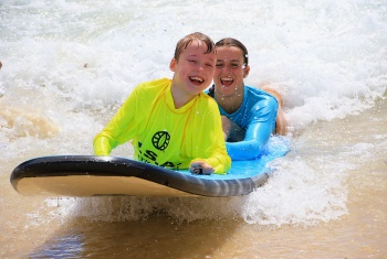 Male child on surfboard supported by female support worker Imogen