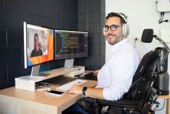 Santi Martinez sitting at his desk in front of two computer screens 