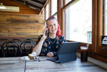 Tahlia Blanshard with her phone and device at a cafe.