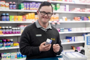 Patrick at the counter of the pharmacy he works in